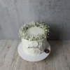 Beyaz çiçeklerden çelenkle süslenmiş beyaz pasta