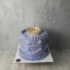 Altın renkli taç ve inci süslemeleri bulunan mor pasta