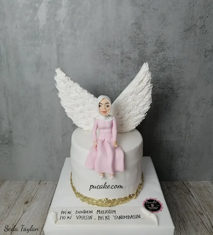 Beyaz melek kanatları ve pembe elbiseli kadın figürüyle süslenmiş pasta
